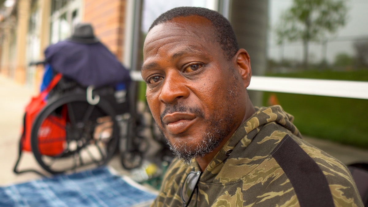 Portrait of a homeless Black man, sitting outdoors