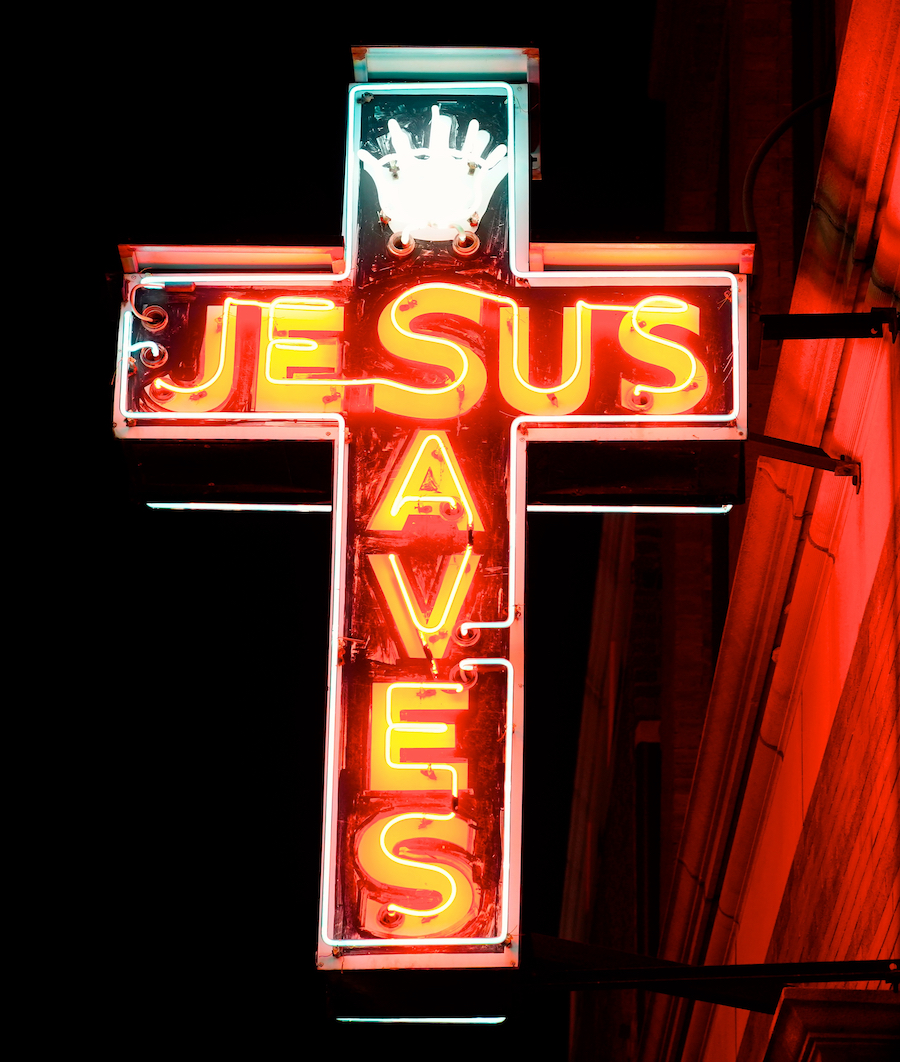 A neon cross with the words 'Jesus Saves' inside it.