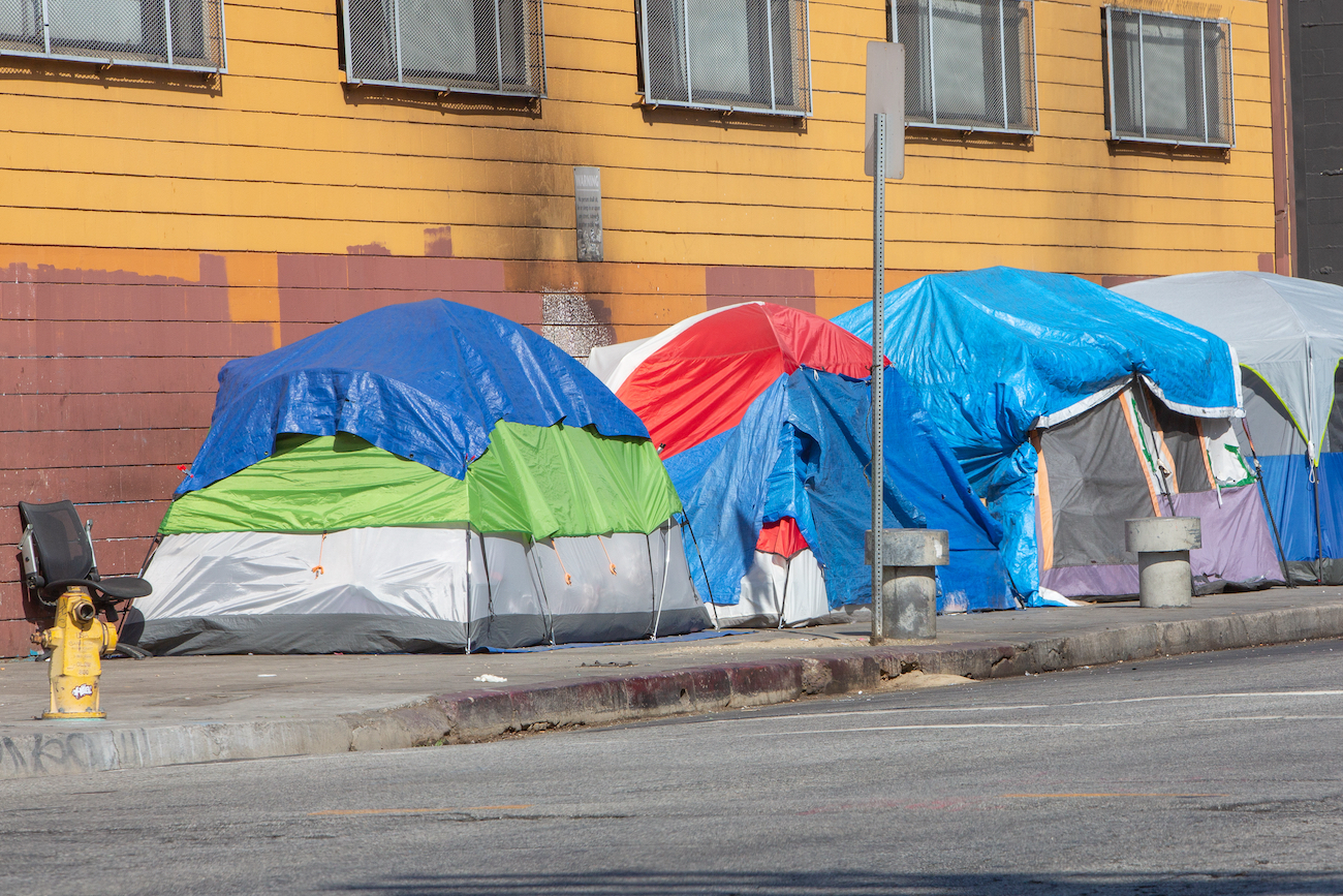 A row of tents are on a city sidewalk