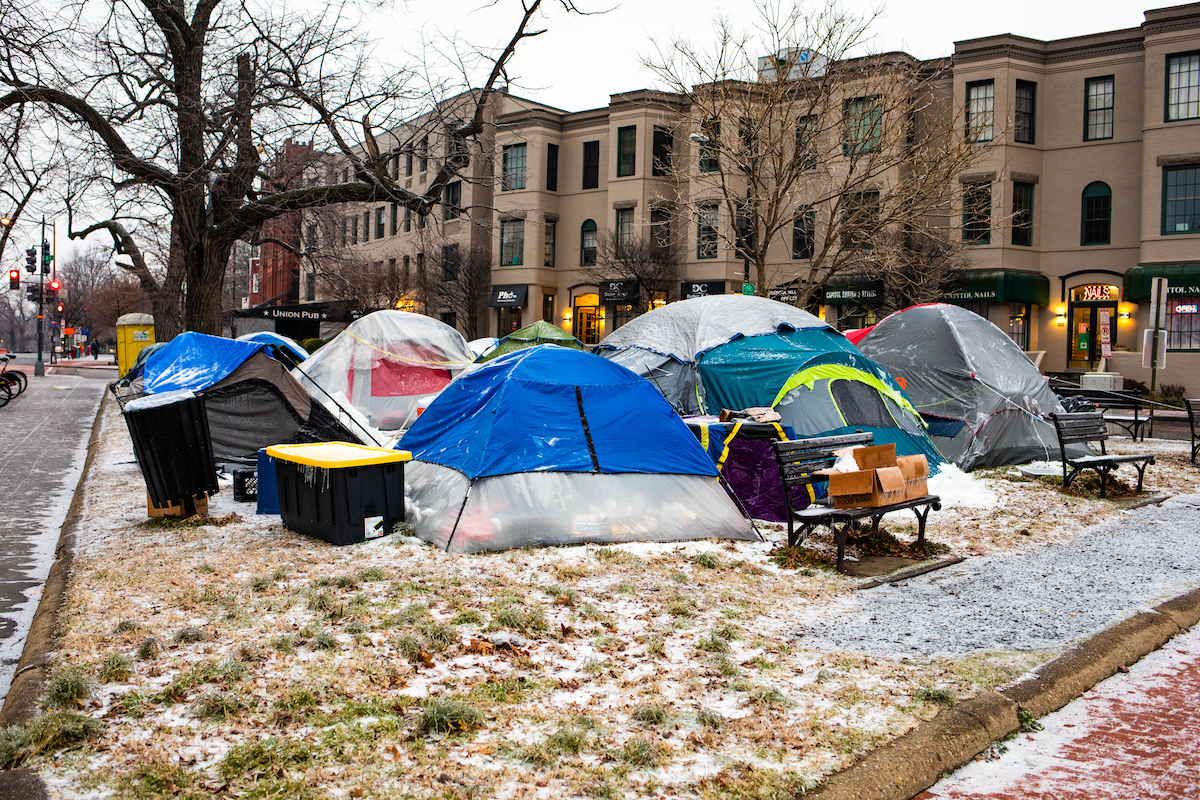 A group of tents at a homeless encampment in a park, covered in snow.