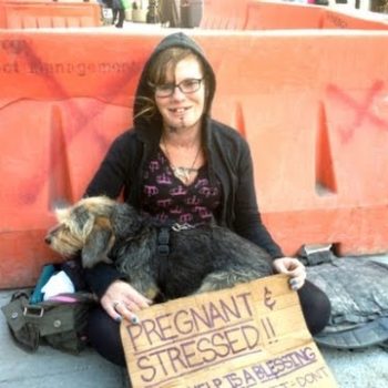 Homeless womans sign reads PREGNANT STRESSED as she sits begging for change in San Francisco