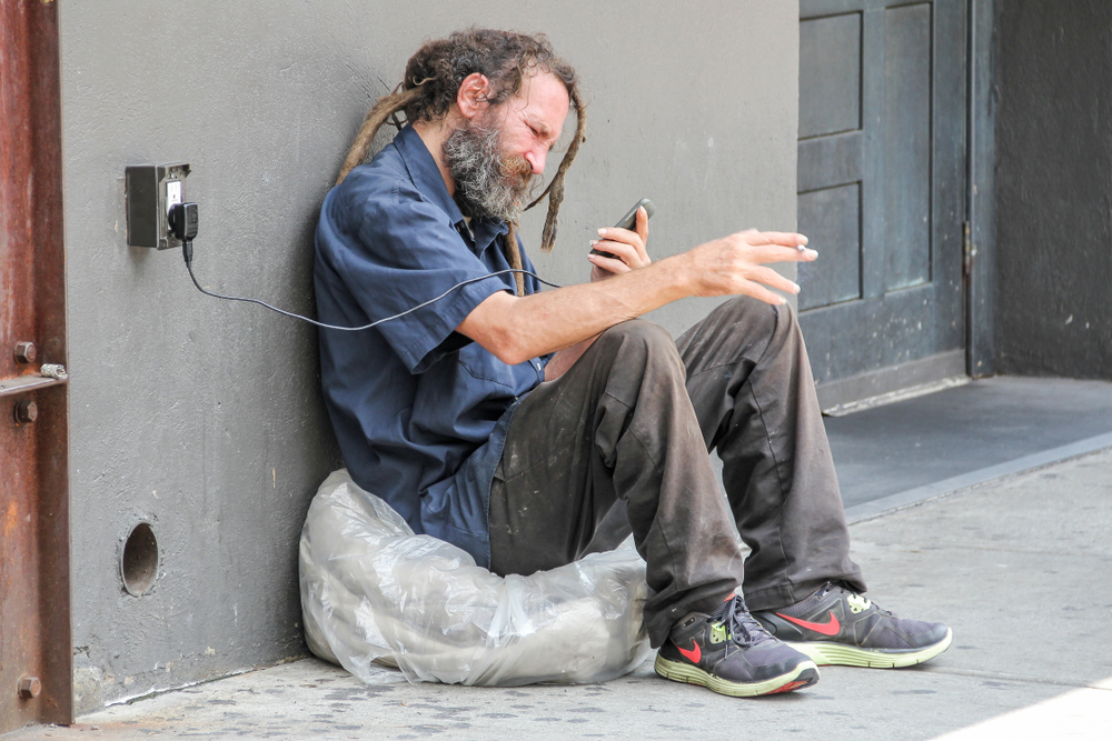 homeless man using cell phone