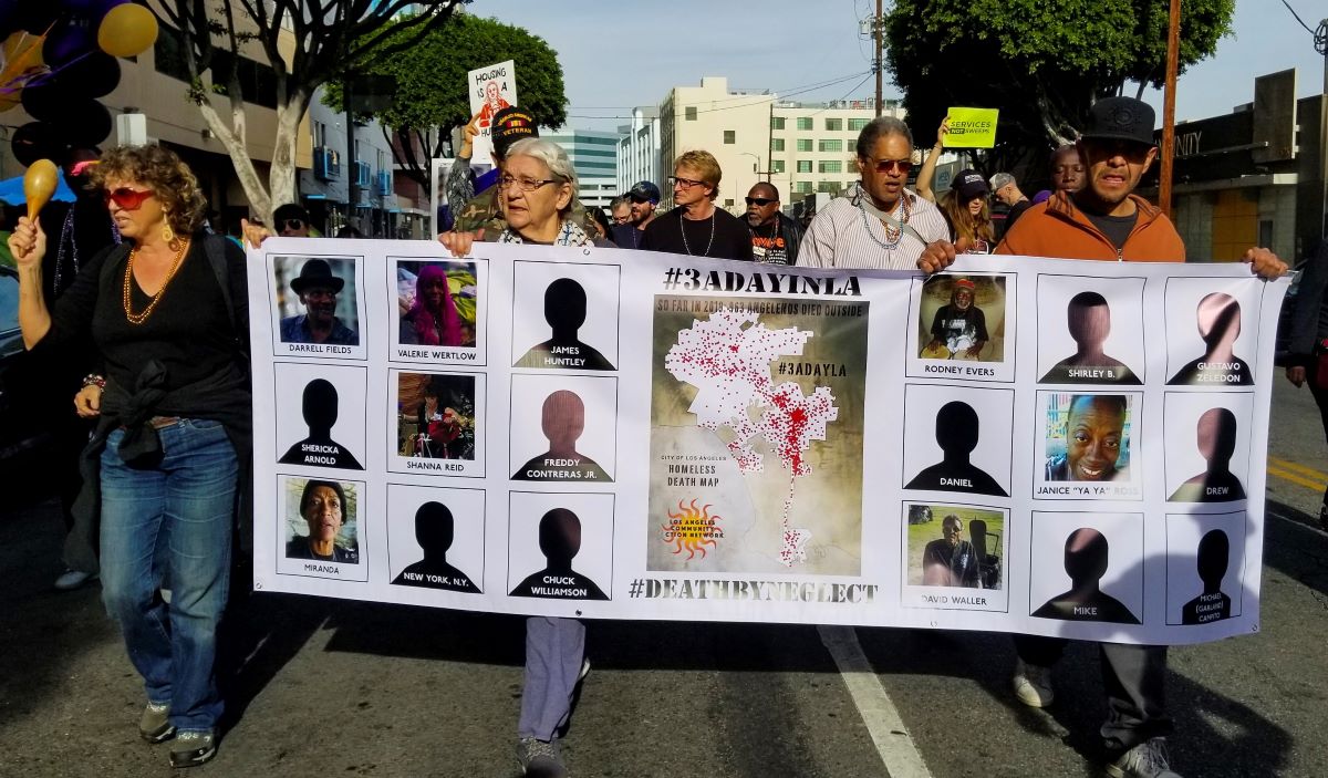 Organizers hold a banner depicting some of the names of people that died while living on the streets in 2019