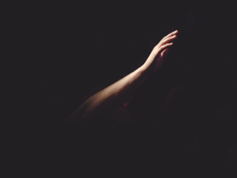 arm reaching out from the dark into the light