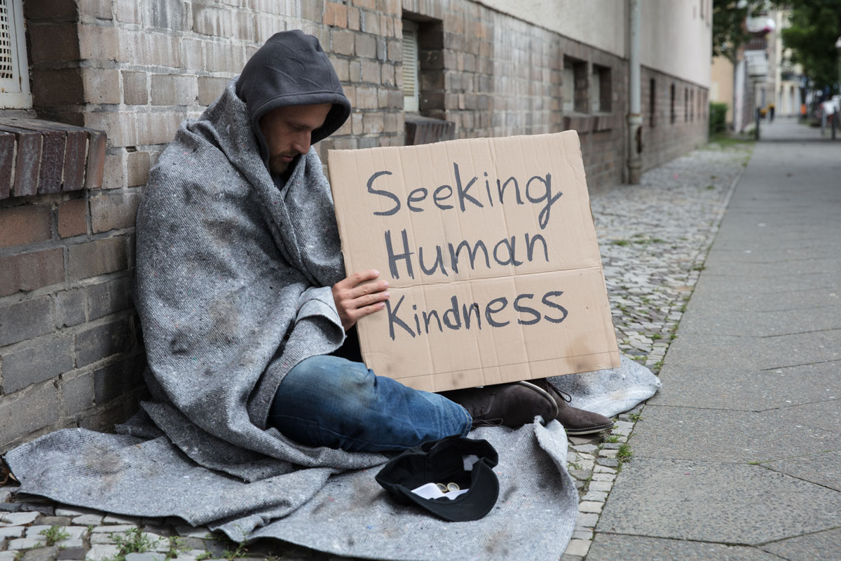 seeking human kindness sign held by homeless man