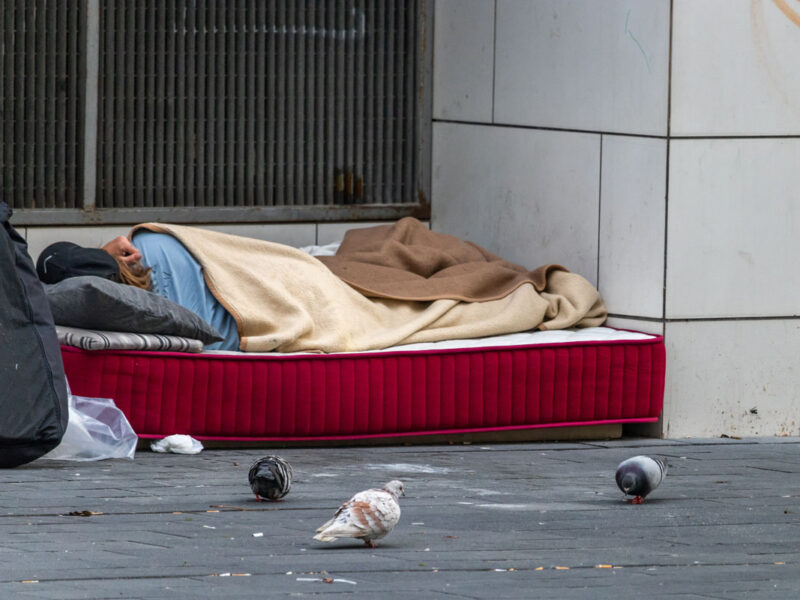 Homeless woman sleeping on mattress in spain