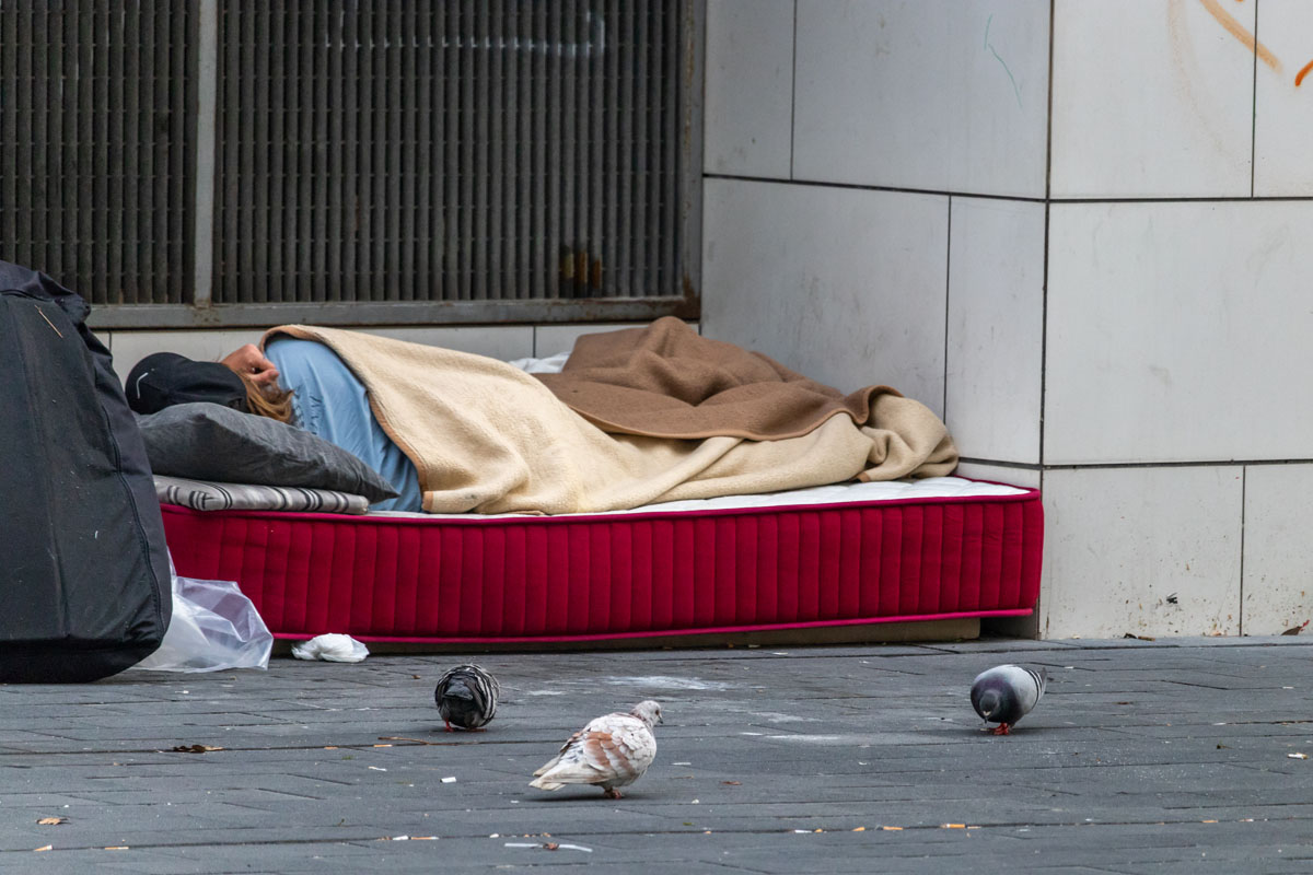 Homeless woman sleeping on mattress in spain