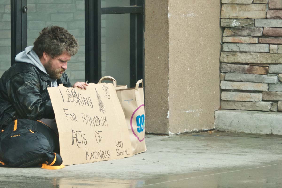homeless man holds a sign