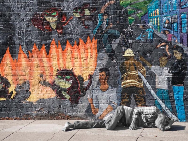 homeless person sleeps in front of San Francisco Mural