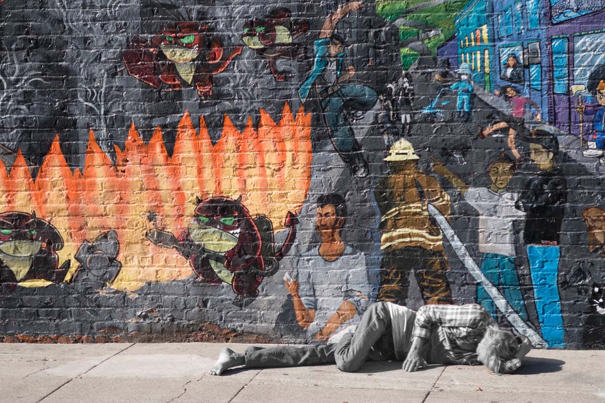 homeless person sleeps in front of San Francisco Mural