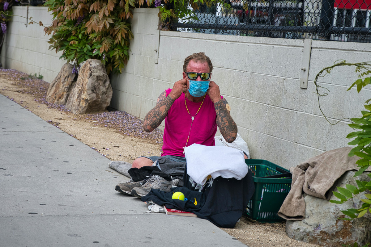homeless man puts on his coronavirus mask