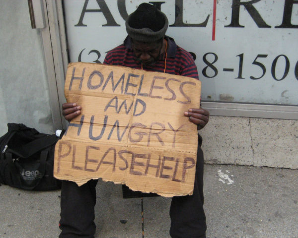 man holds homeless and hungry sign