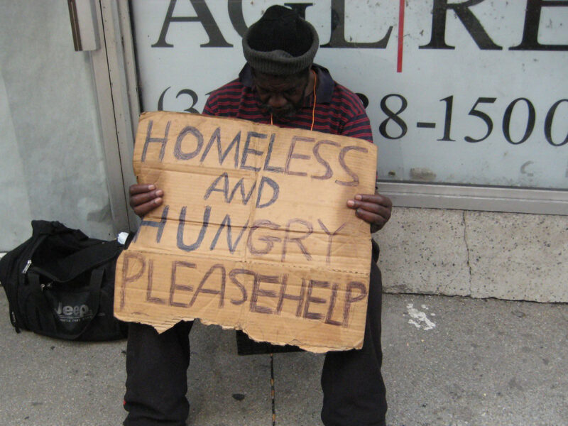 man holds homeless and hungry sign