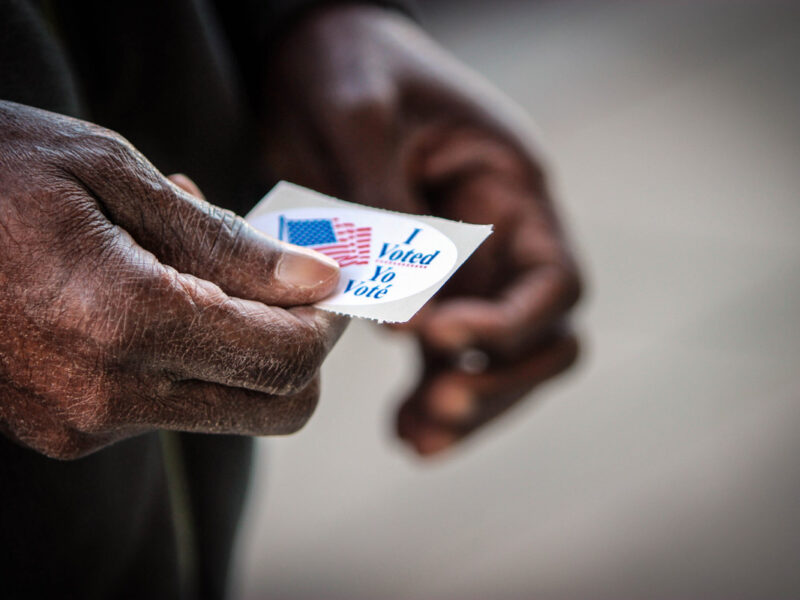 elderly man holds vote sticker