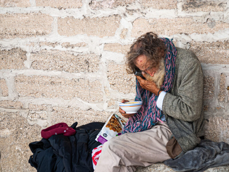 elderly homeless man uses his cellphone