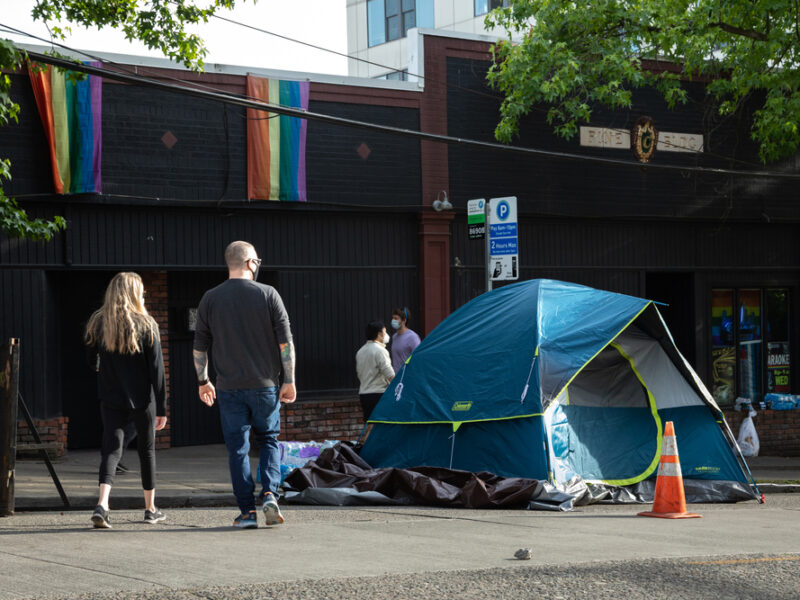 People walk by homeless tents in Seattle. The public doesn't believe housing first works